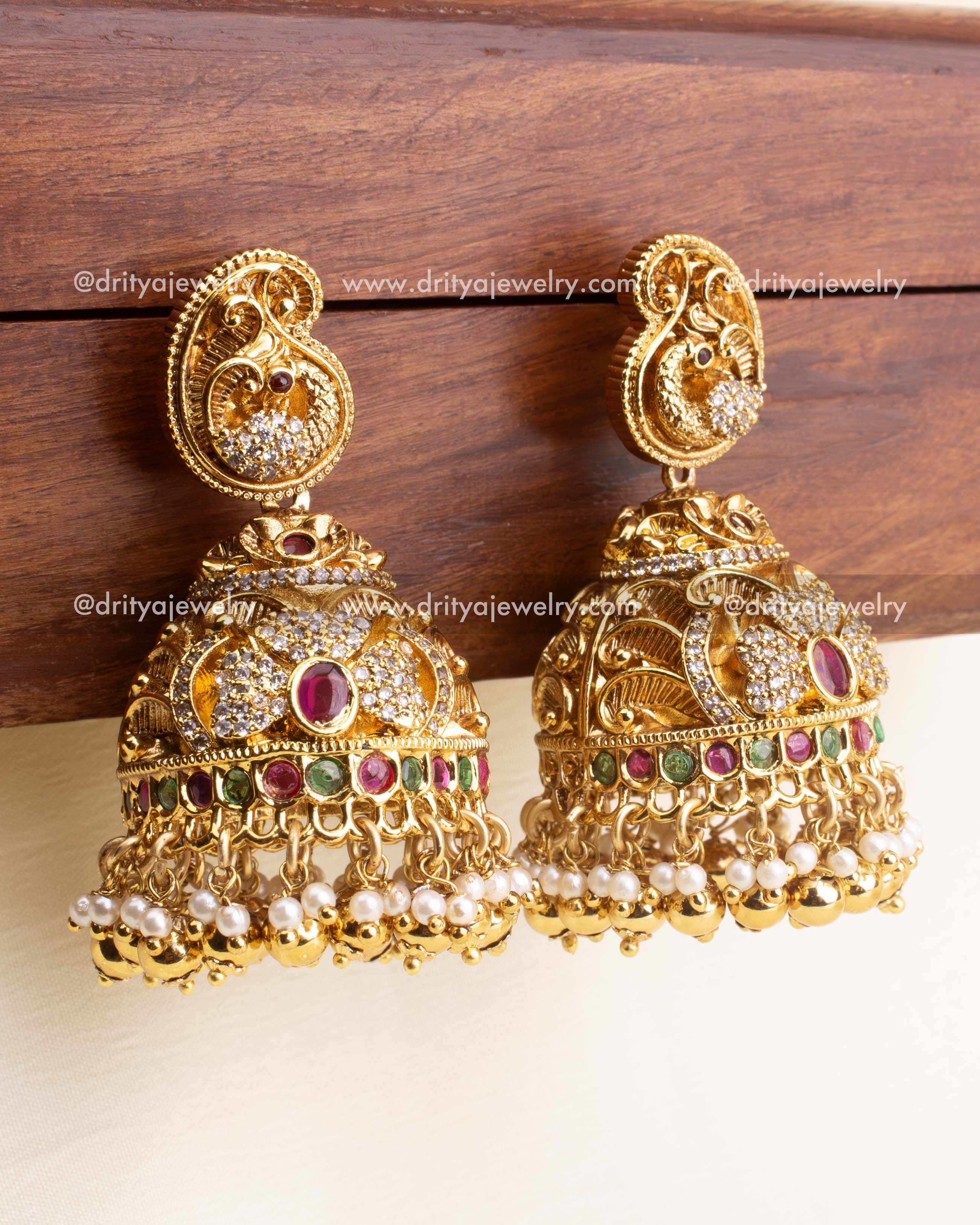 Heavy bridal jhumka earrings with ruby red, green stones, CZ accents, and pearl drops.