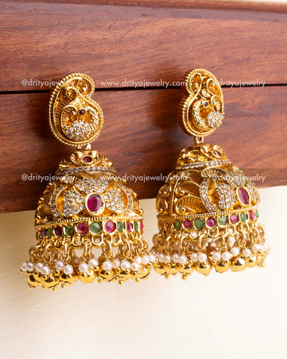 Heavy bridal jhumka earrings with ruby red, green stones, CZ accents, and pearl drops.