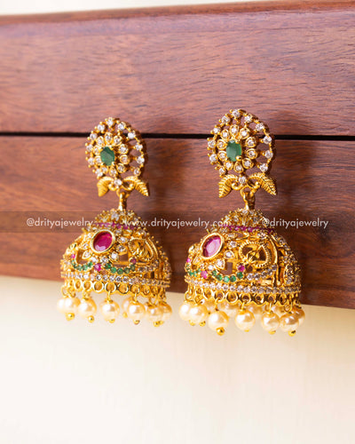 Detailed view of bridal jhumkas featuring colorful stones and pearl hangings.