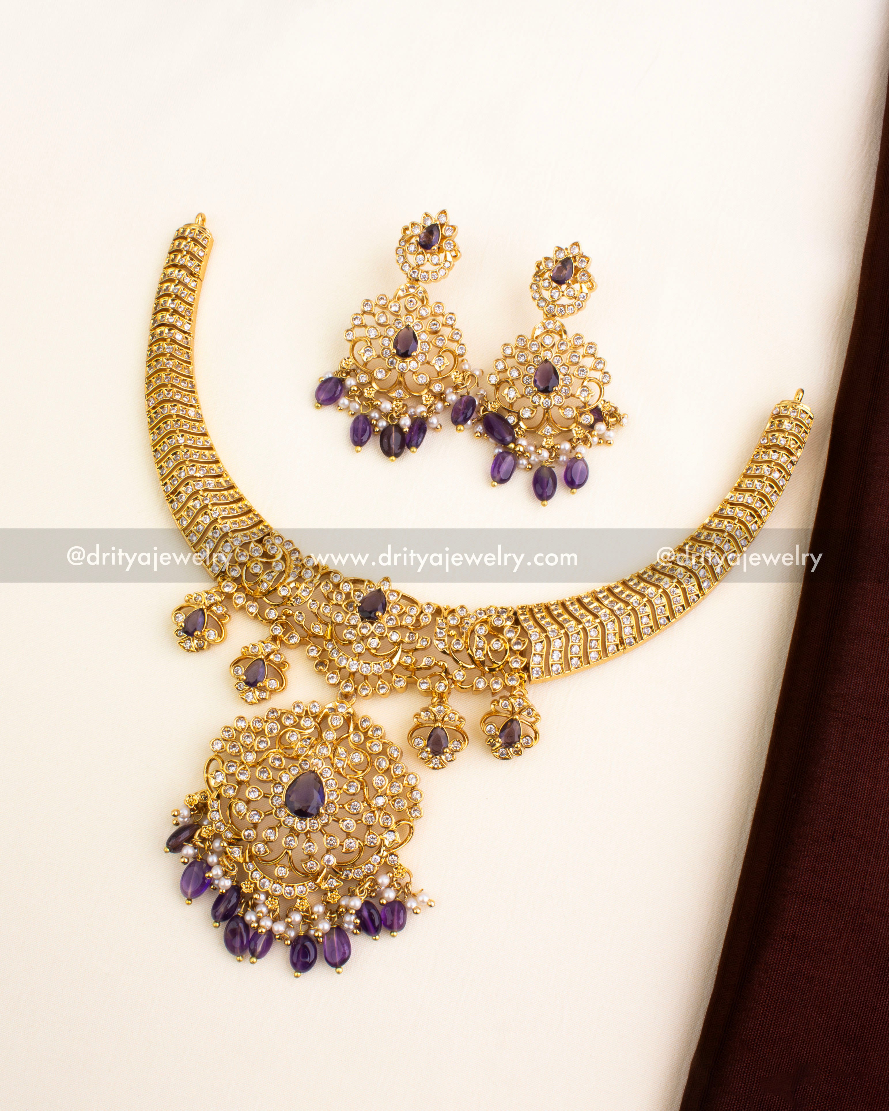 Short gold-plated necklace set featuring CZ stones, purple center drops, and matching earrings.