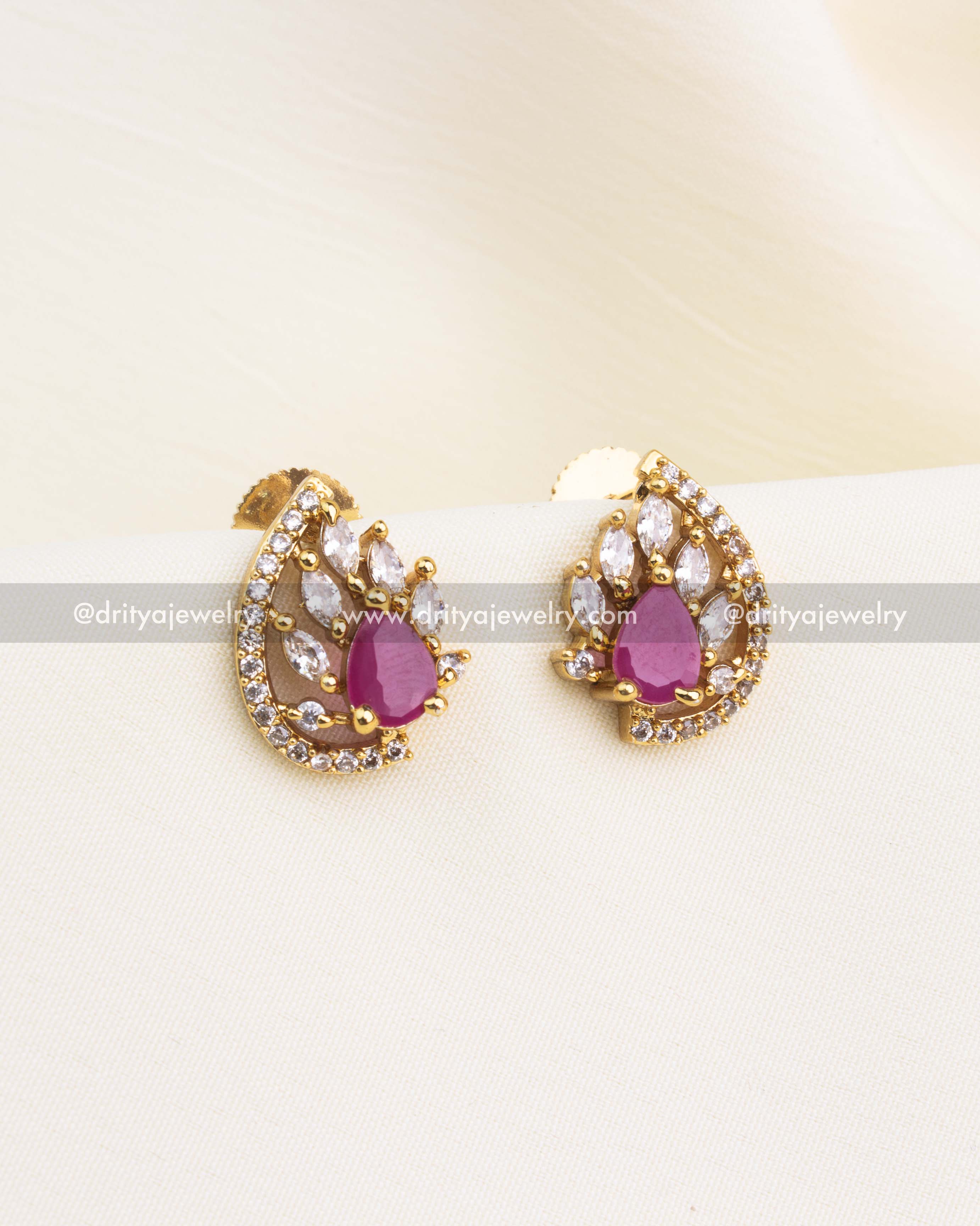 Ruby red stud earrings with gold base and white CZ border.