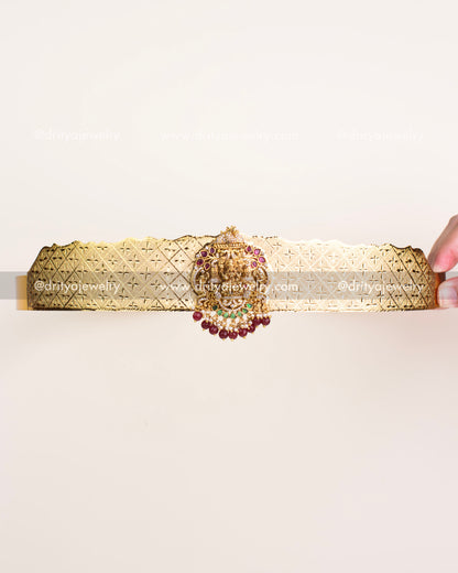 Replica gold temple vadanam with Goddess Lakshmi motif, ruby-emerald accents, and ruby bead hangings.