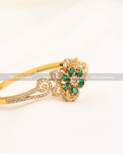 Openable gold kada with green teardrop stones arranged in a floral pattern.