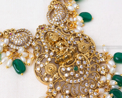 legant short necklace with Lakshmi motif, antique gold polish, and pearl and bead detailing, paired with matching earrings in emerald green or ruby red.