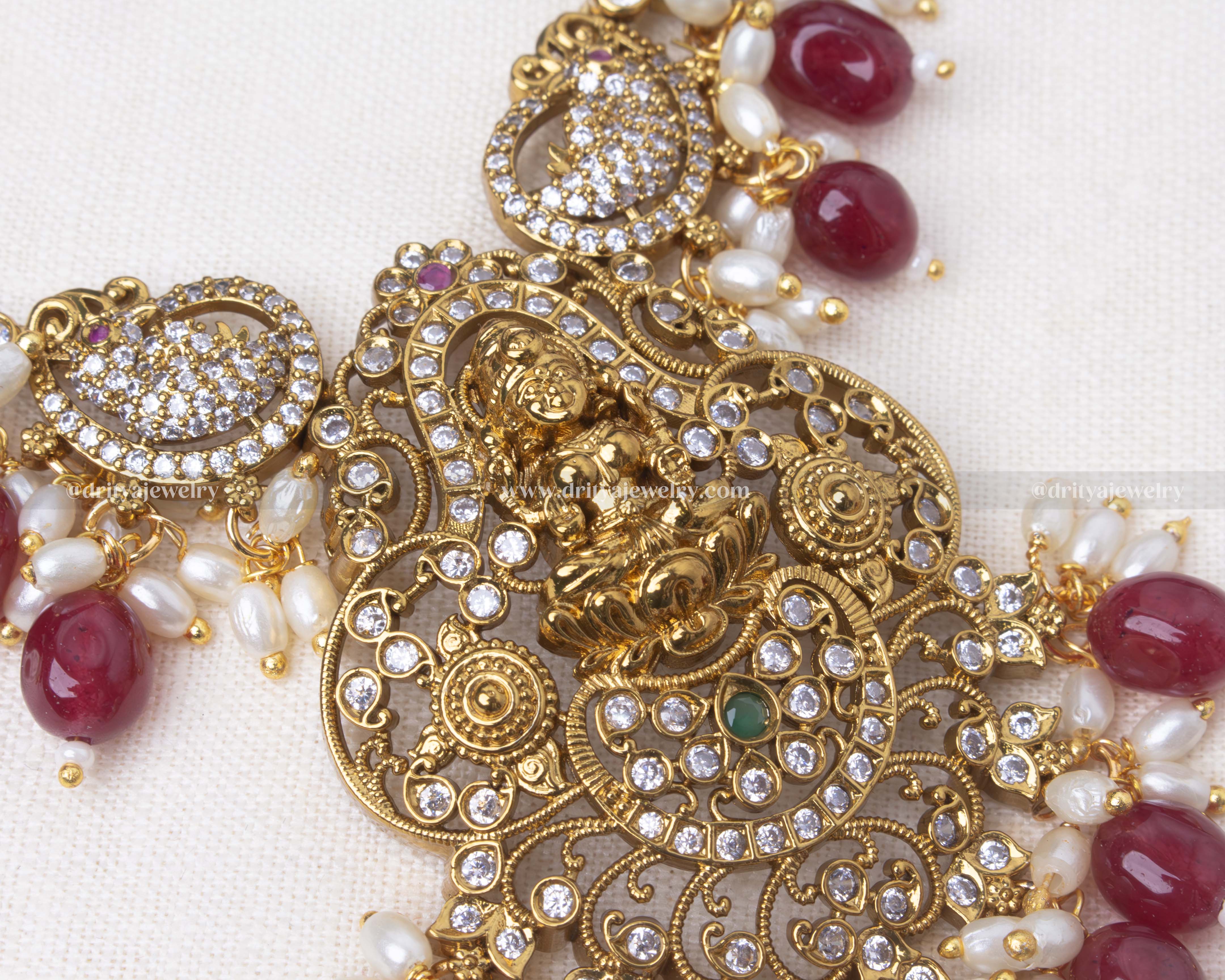 legant short necklace with Lakshmi motif, antique gold polish, and pearl and bead detailing, paired with matching earrings in emerald green or ruby red.