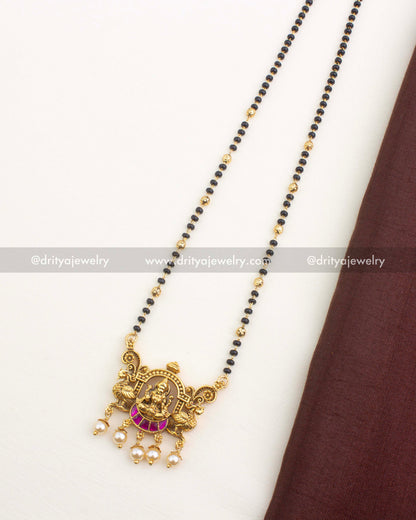 Antique gold Lakshmi pendant necklace with black beads, kemp stones, and pearl drops, 18-inch length.