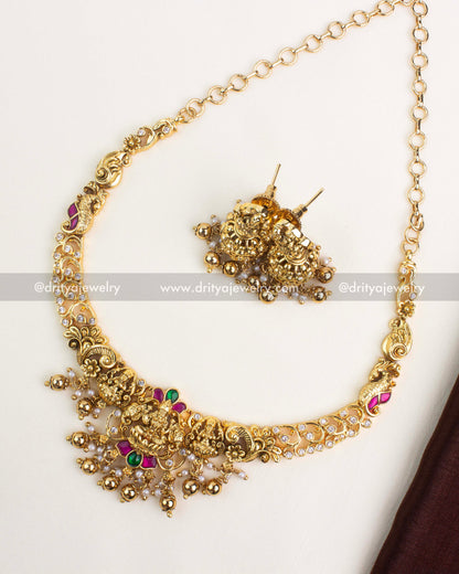 Antique gold short necklace set with Lakshmi motif pendant, kemp stones, and matching jhumkas.