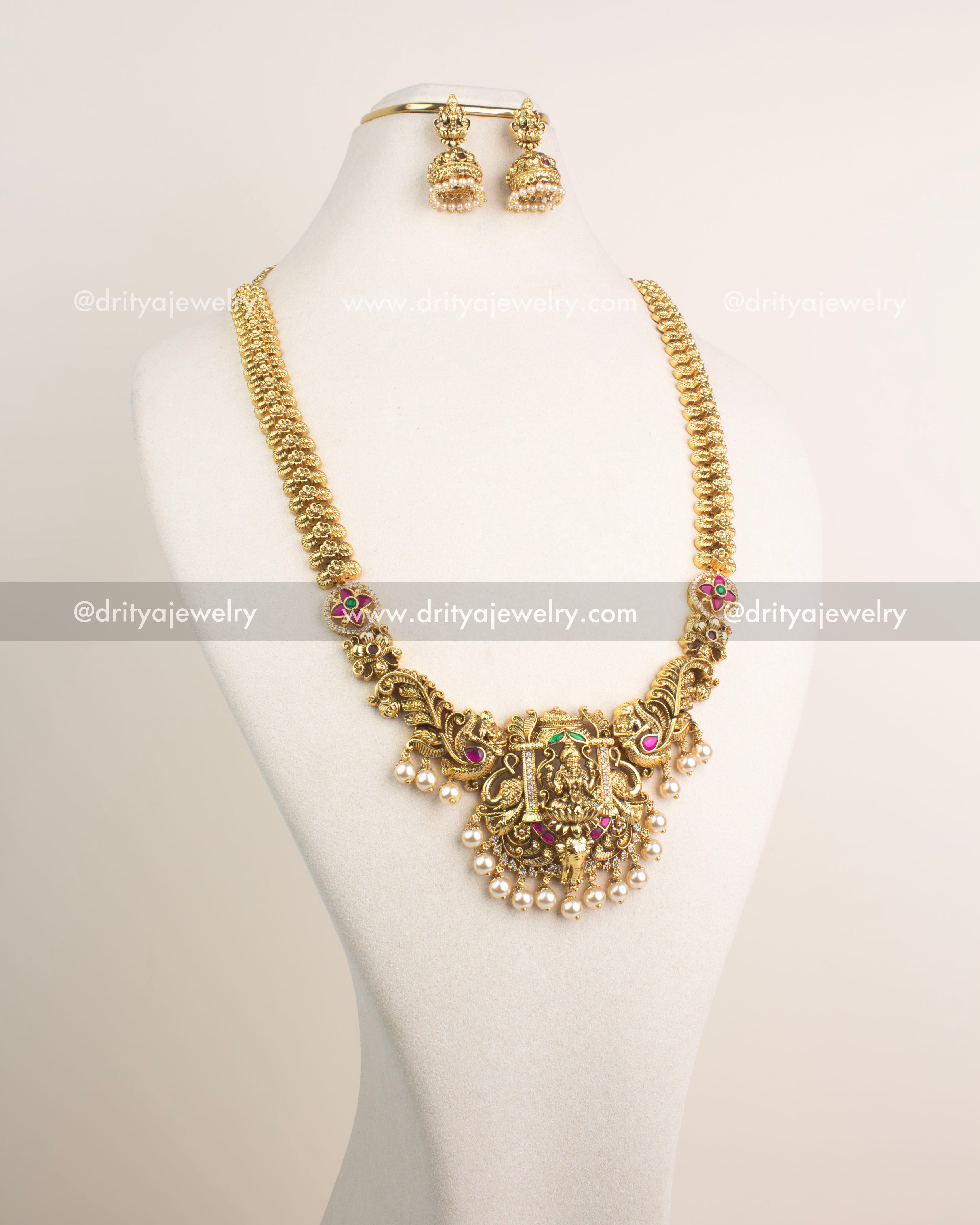 Antique gold temple long haram with Lakshmi Devi pendant, ruby and emerald Kemp stones, and pearls.