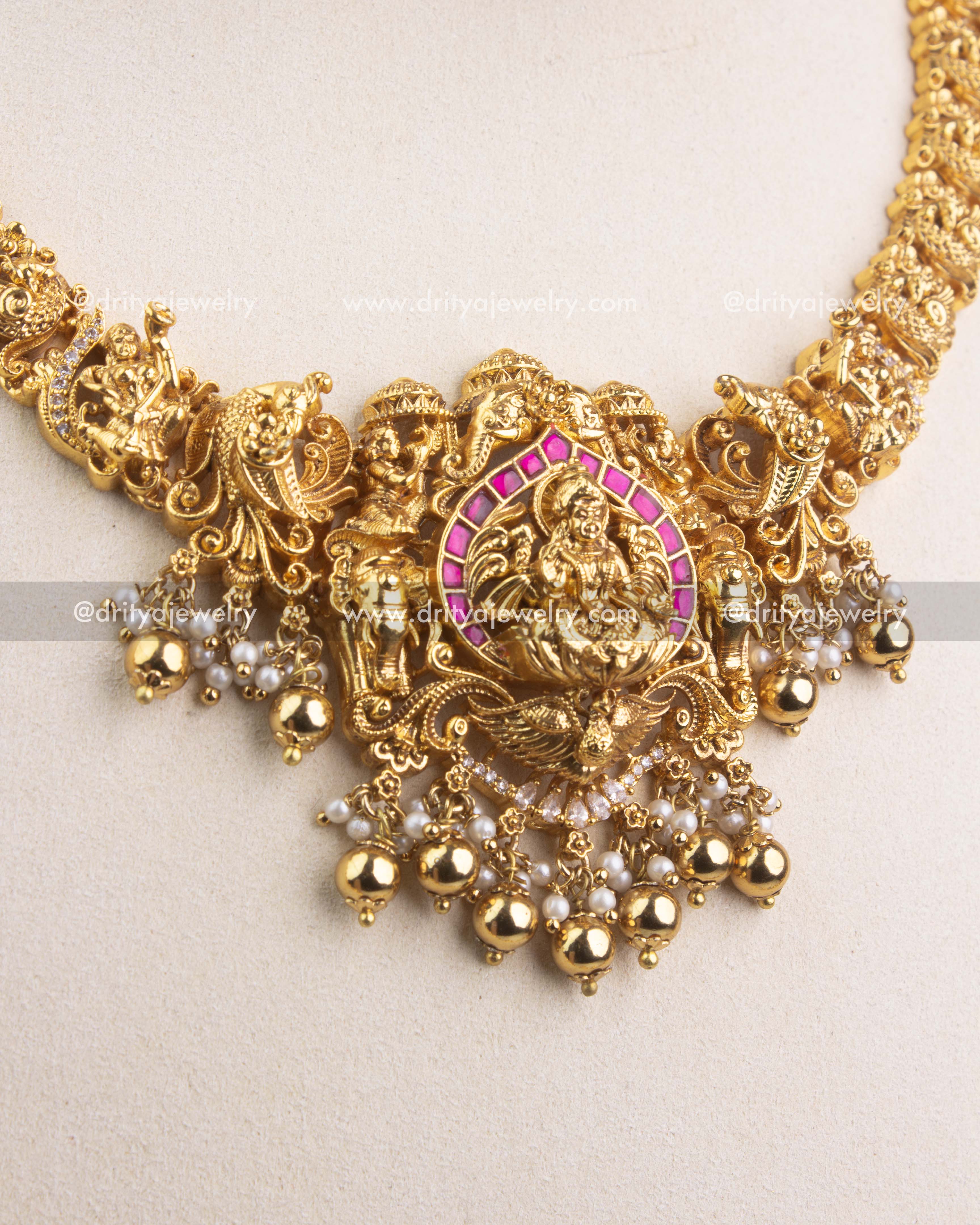 Detailed view of Lakshmi Devi Nakshi pendant with ruby Kemp stones and pearl hangings.