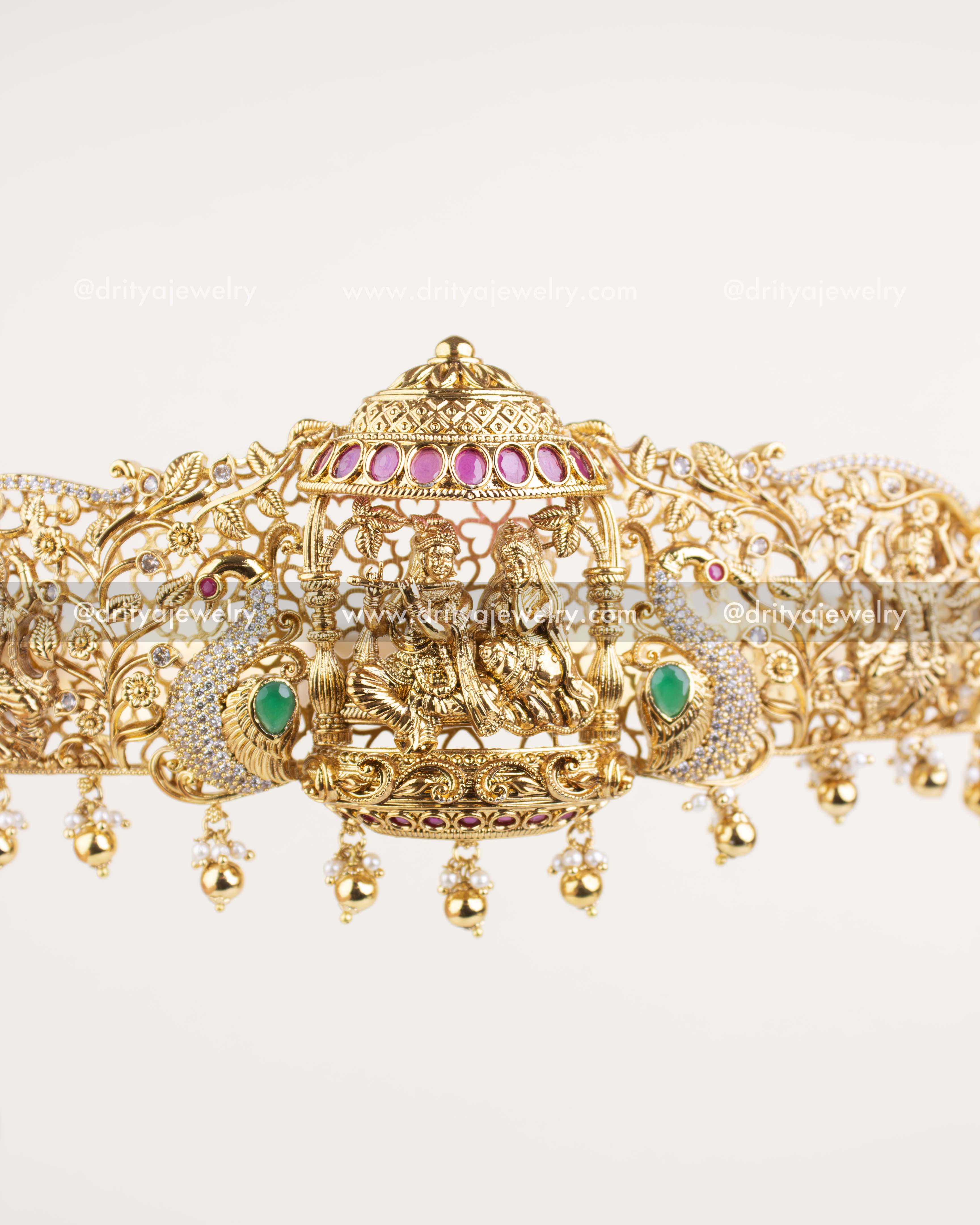 Krishna-themed waist belt in antique gold with peacock accents, dome motif, and pearl hangings.
