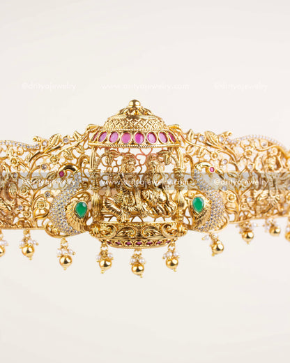 Krishna-themed waist belt in antique gold with peacock accents, dome motif, and pearl hangings.