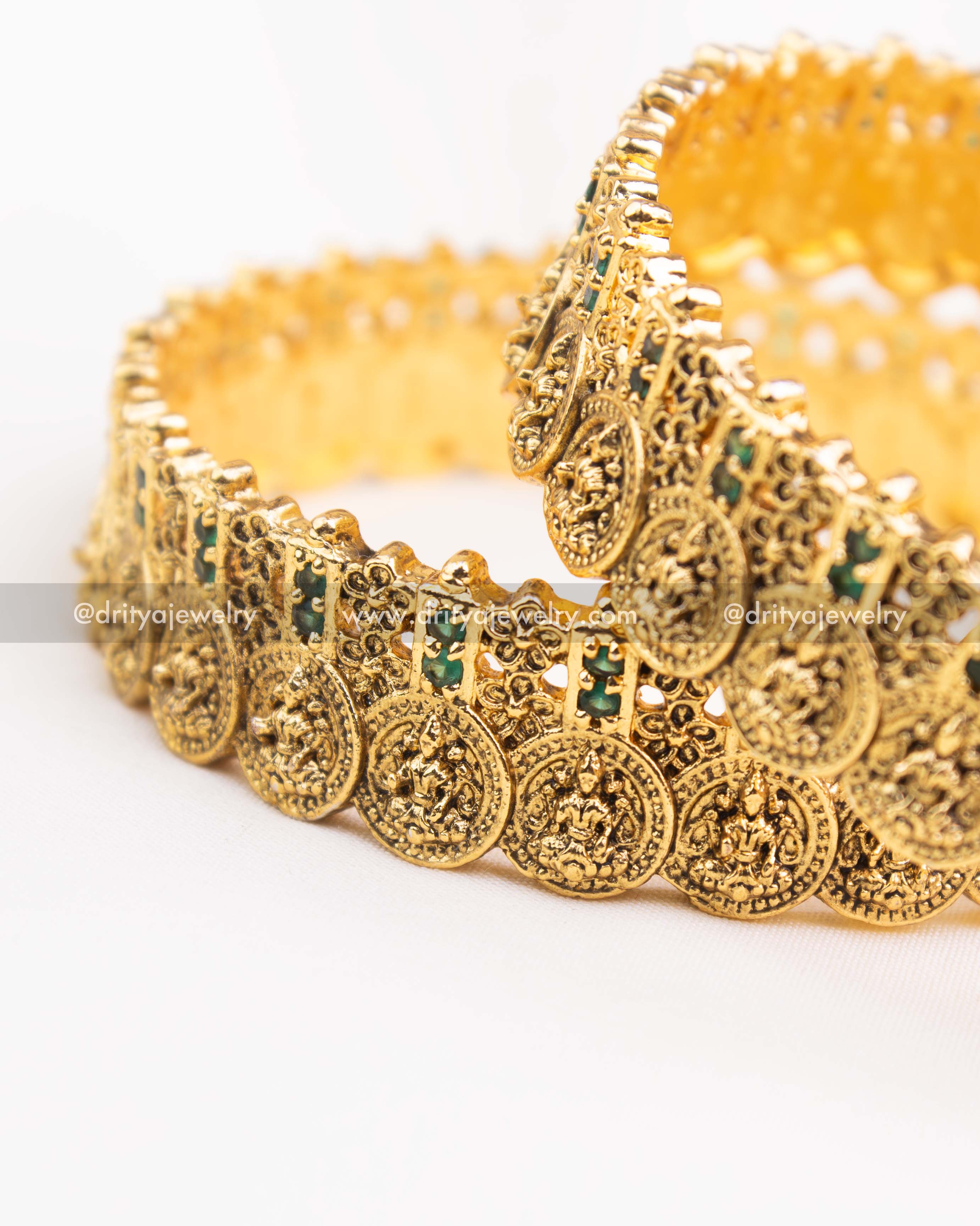 Side angle showing the intricate green stone placement and coin pattern on nakshi bangles.