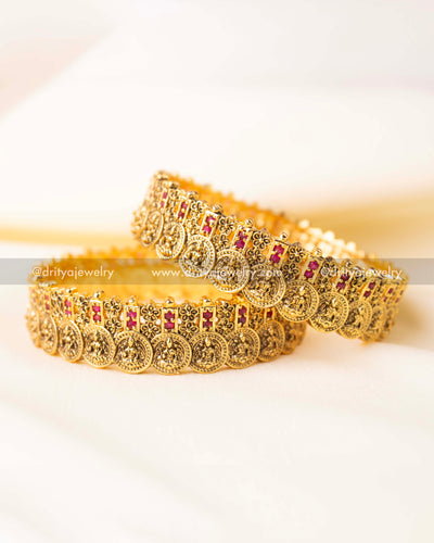 Close-up of traditional temple-style Nakshi carving with embedded ruby red stones.