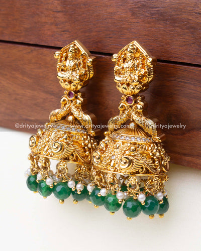 Big size nakshi Jhumka earrings featuring a detailed goddess motif, peacock carvings, and green bead drops.
