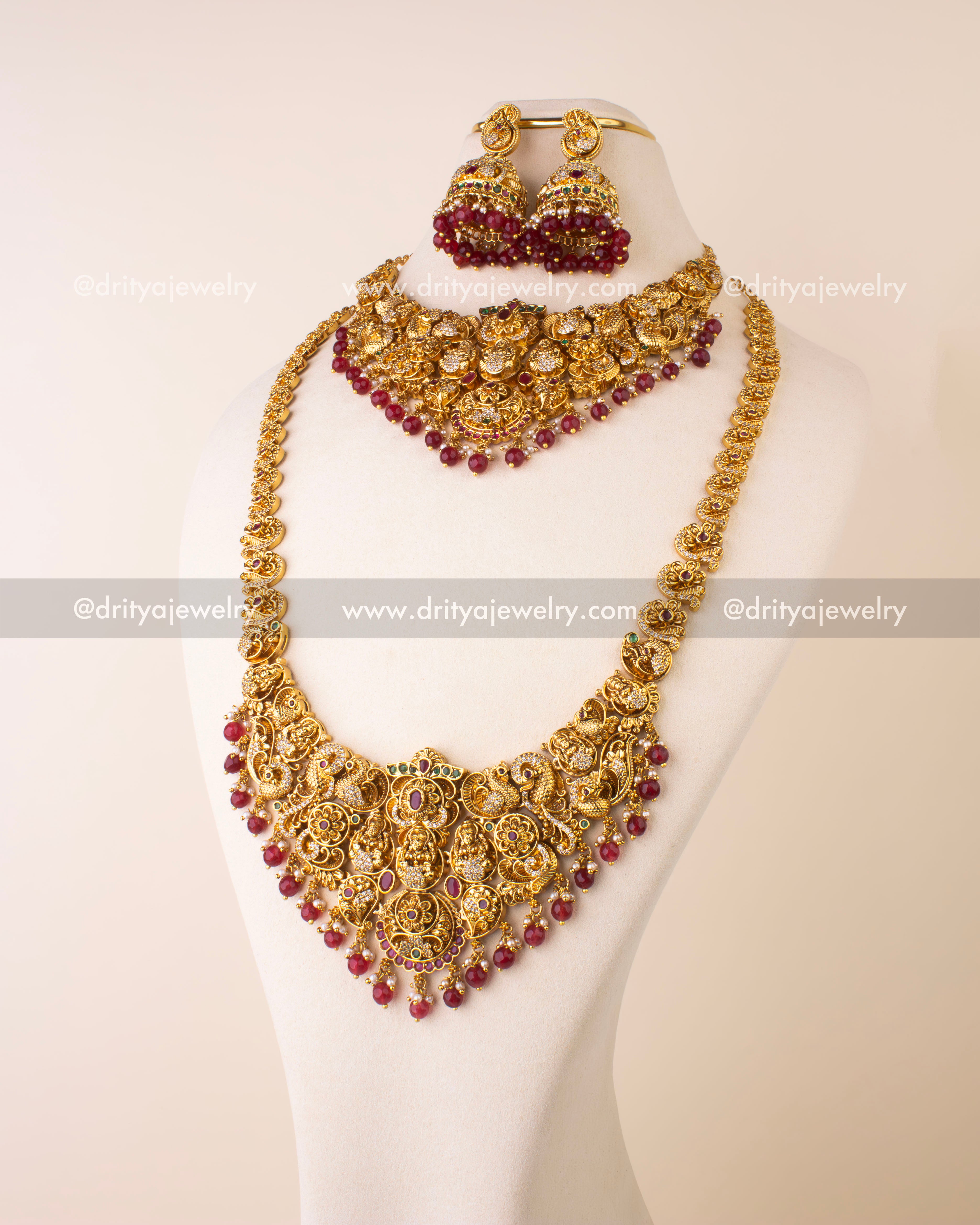 Bridal Nakshi jewelry set featuring long necklace, short necklace, jhumkas, and maang tikka with ruby beads and antique gold finish.