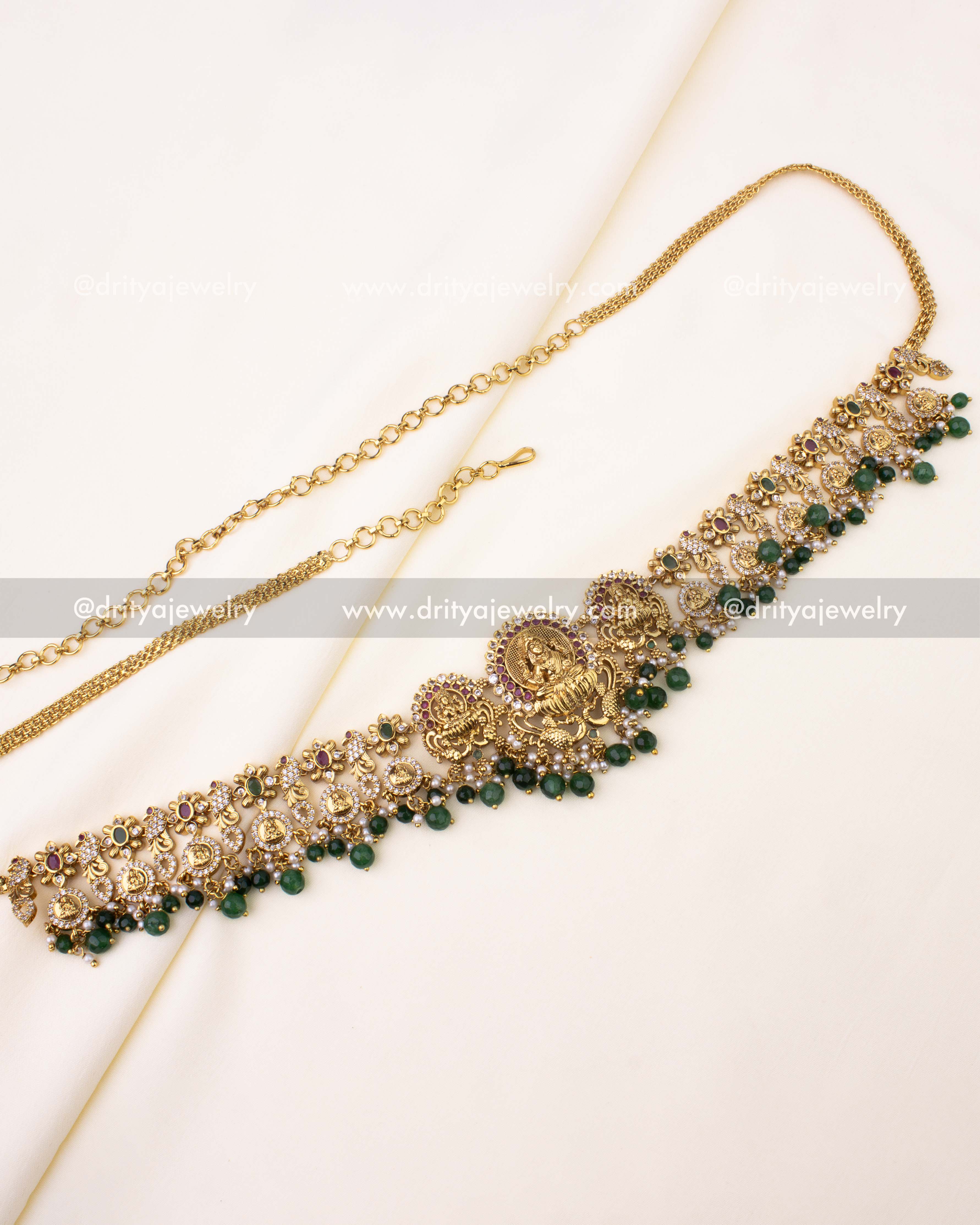Gold-plated Nakshi hip chain with Goddess Lakshmi motifs, ruby-green accents, and bead drops.