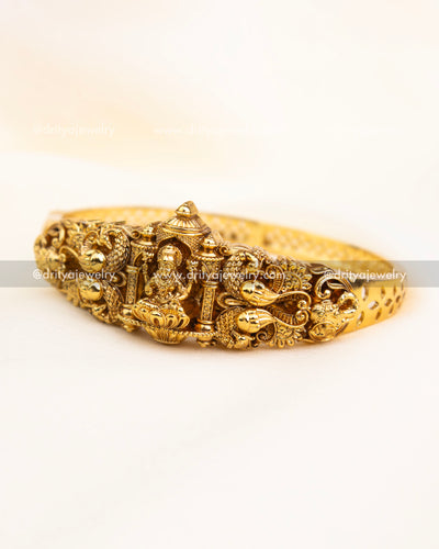 Gold-plated openable kada with Lakshmi Devi motif, temple carvings, and antique finish.