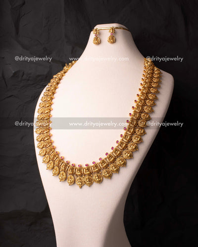 Traditional long nakshi haram with Lakshmi motifs and ruby accents displayed on mannequin.
