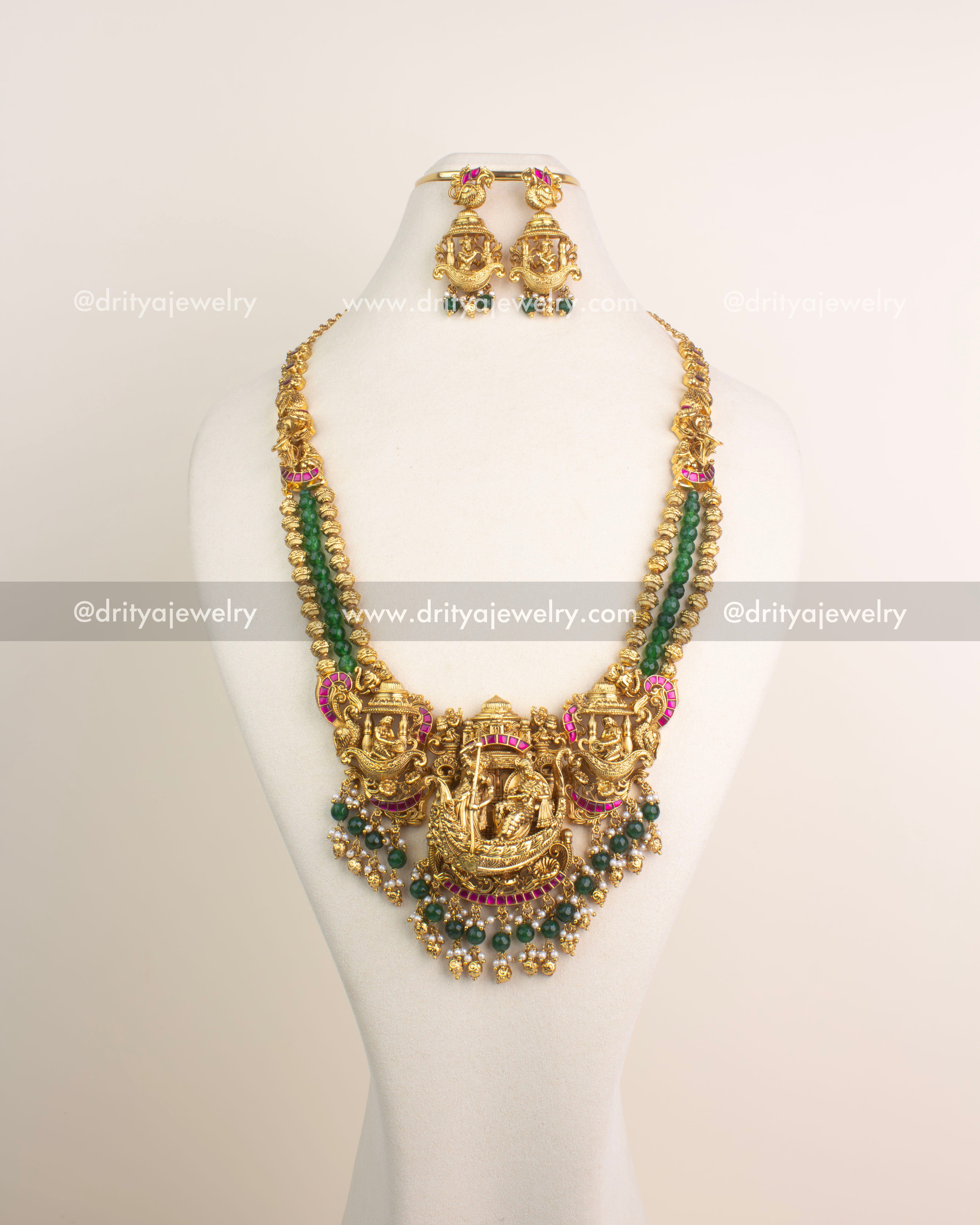 Antique gold Nakshi long haram featuring Lord Krishna boat motif with ruby Kemp stones and emerald green bead hangings.