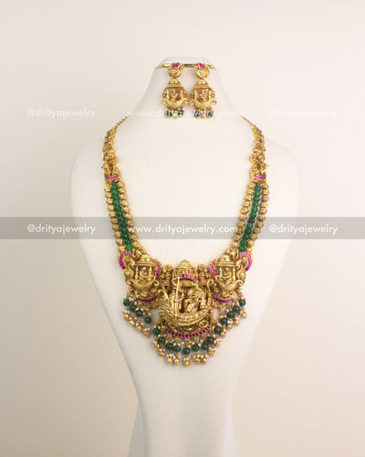 Antique gold Nakshi long haram featuring Lord Krishna boat motif with ruby Kemp stones and emerald green bead hangings.