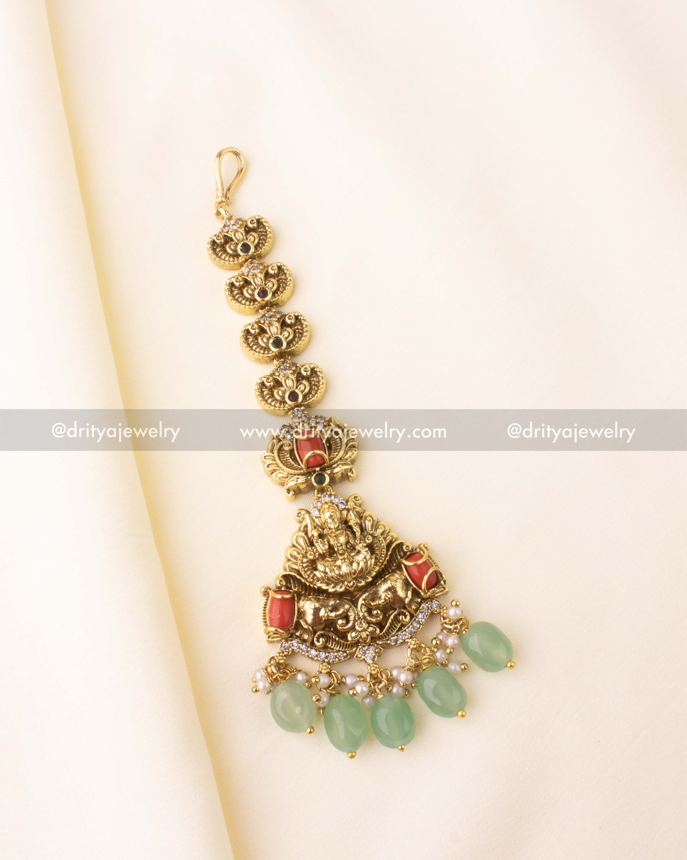 Traditional nakshi maang tikka featuring Lakshmi motif with coral and green bead drops.