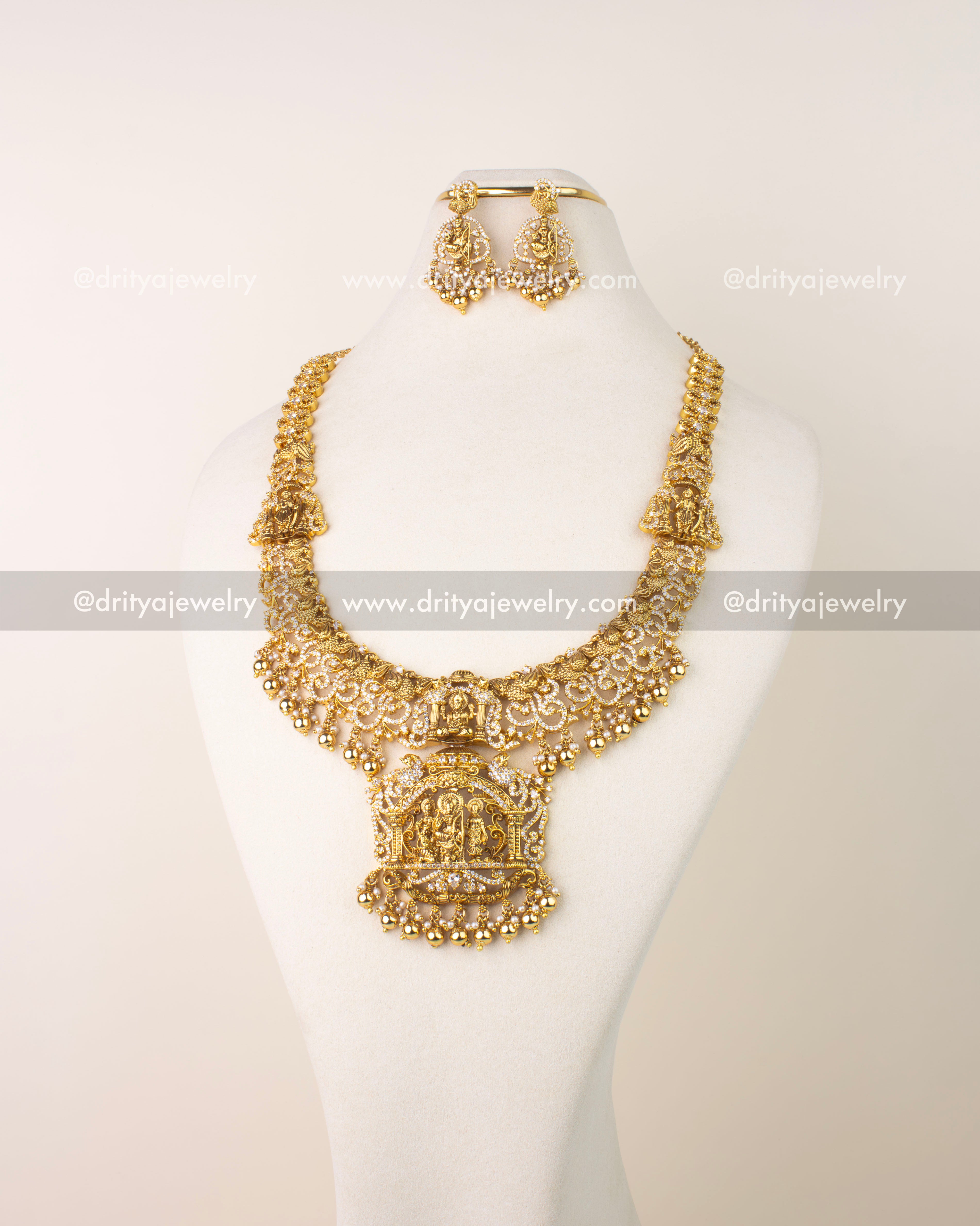 Traditional long haram set featuring Nakshi Ram Parivar motif, AD stones, and pearl drops in antique gold finish.