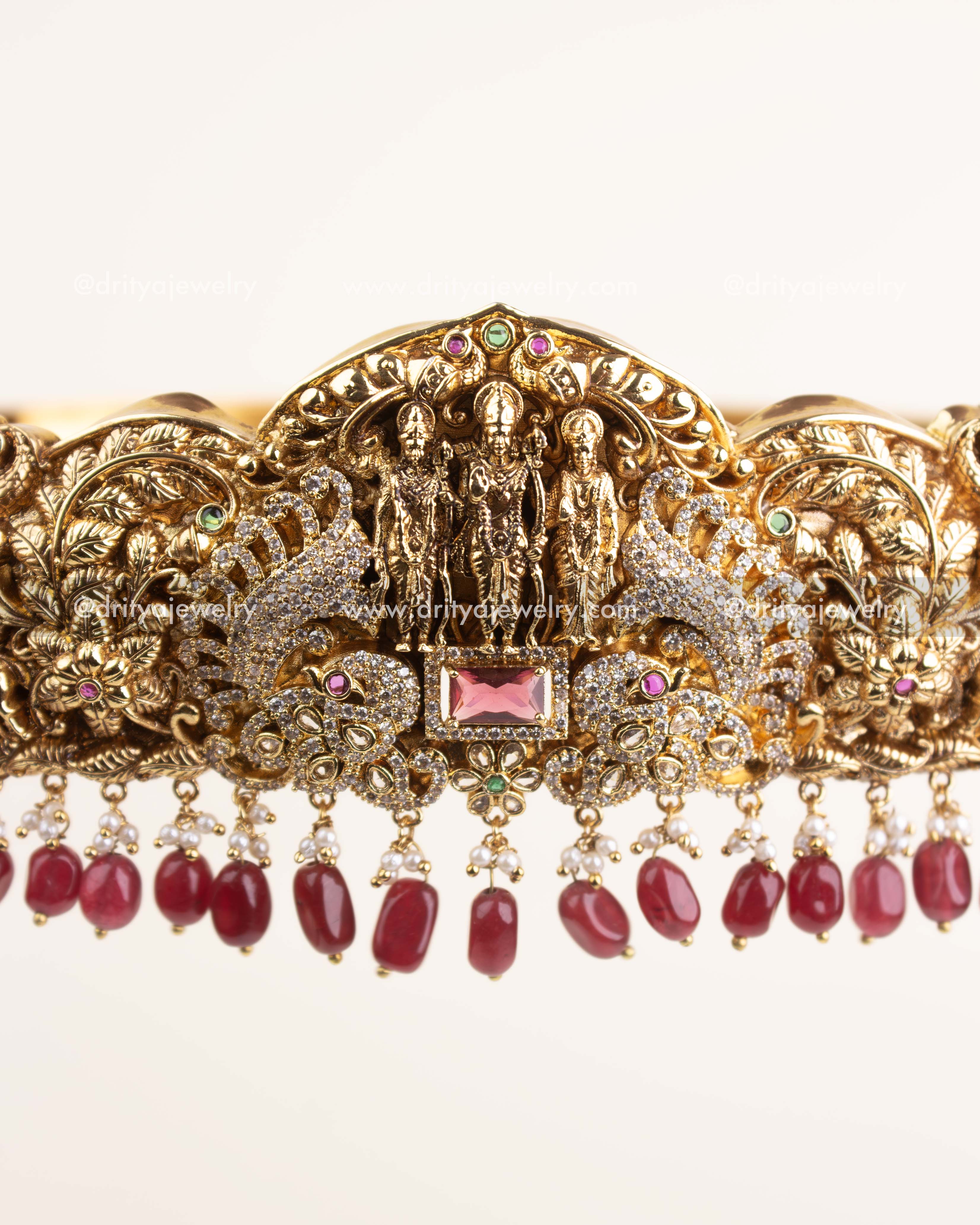 Handcrafted Nakshi detailing with CZ stones, floral carvings, and ruby centerpiece.