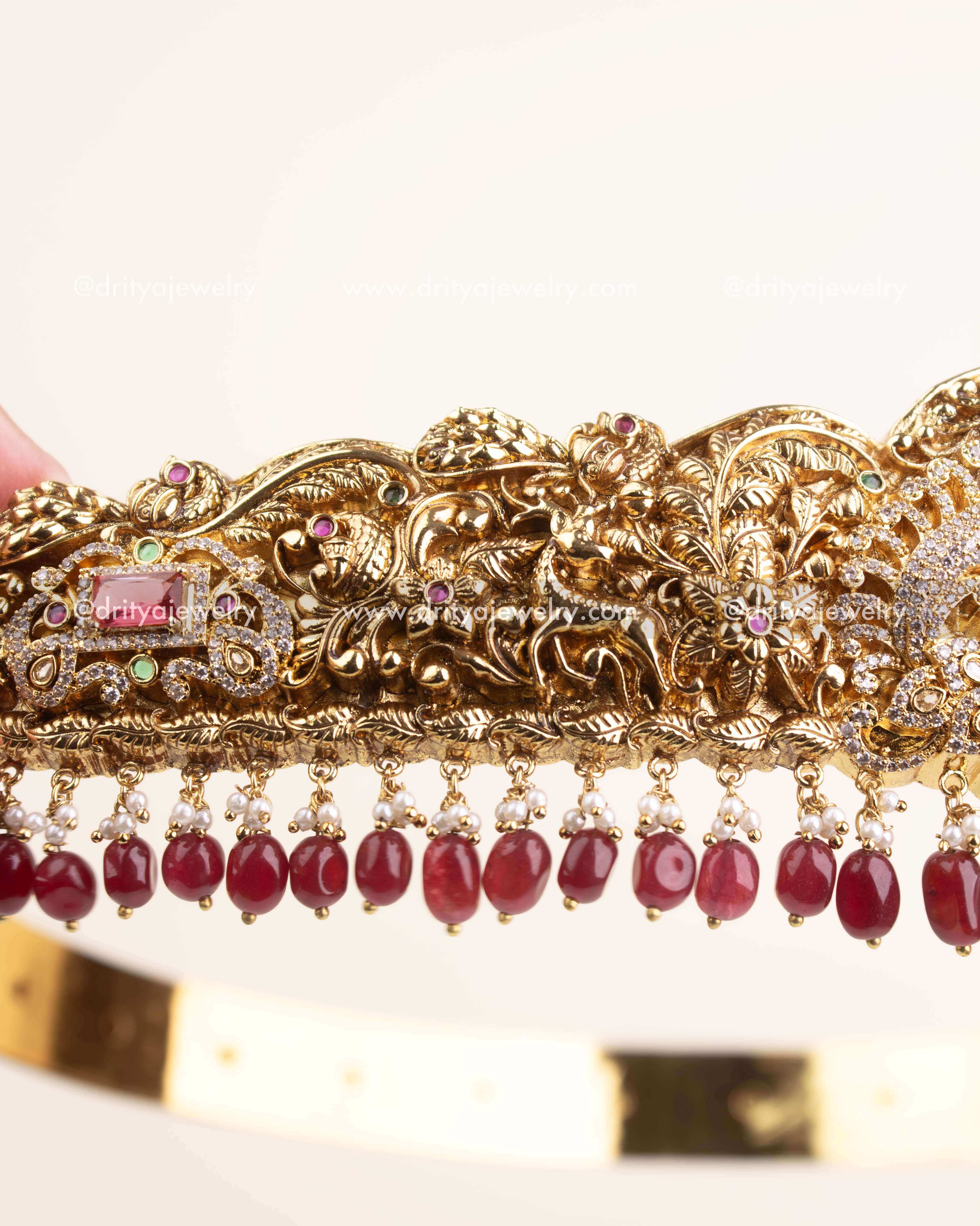 Side view of antique gold temple vadanam showing ruby and pearl hanging embellishments.