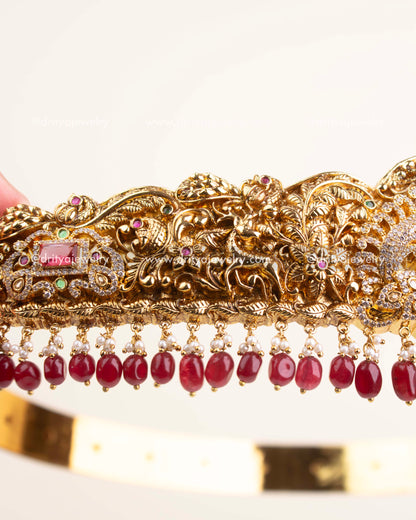 Side view of antique gold temple vadanam showing ruby and pearl hanging embellishments.