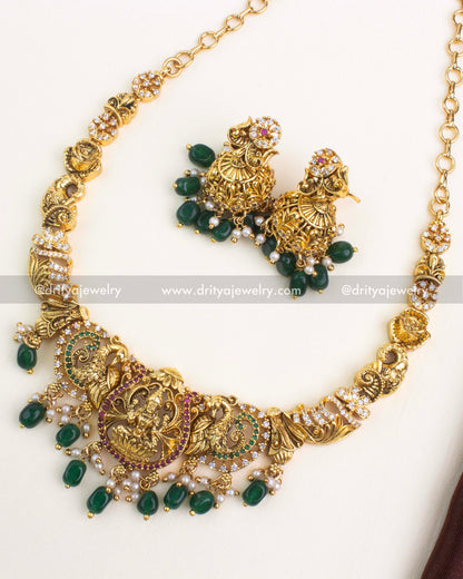 Antique gold Nakshi short necklace set with goddess motif pendant, green beads, and matching jhumkas.