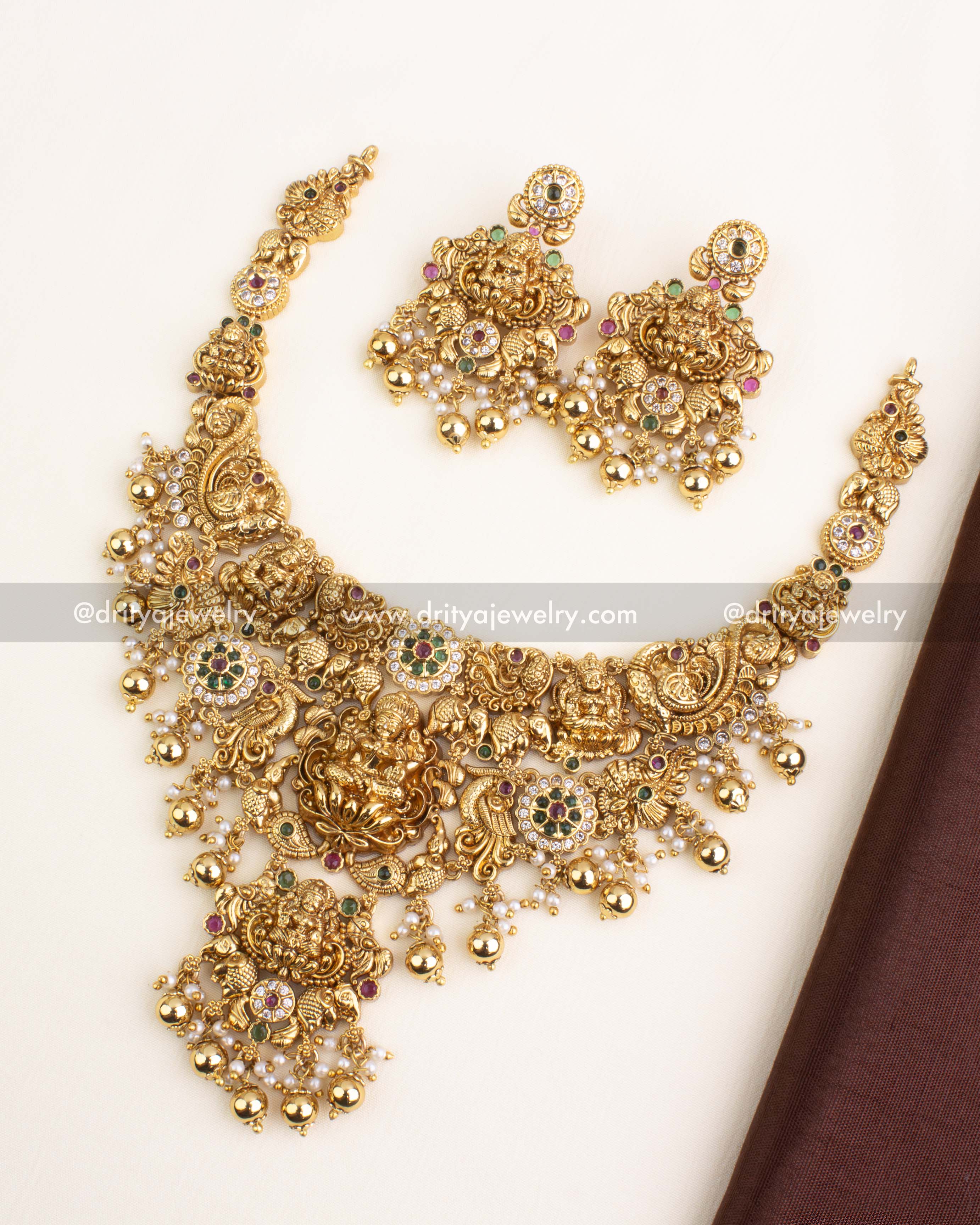 Short antique gold necklace with Lakshmi pendant, peacock and elephant motifs, and golden ball drops.