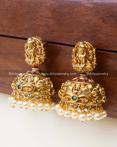 Small nakshi Jhumka earrings featuring goddess carving, peacock motifs, green stones, and pearl hangings.