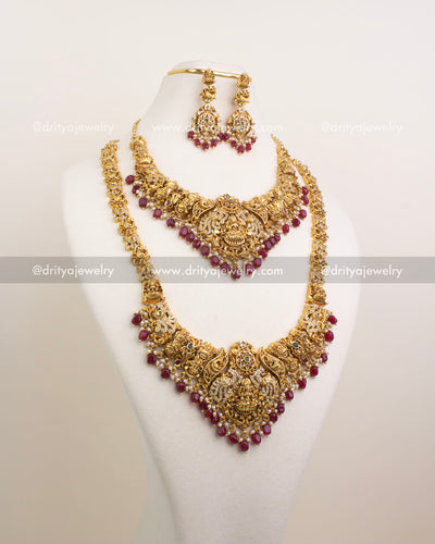 South Indian temple bridal set with ruby red beads, featuring long and short necklaces, earrings, and maang tikka in antique gold finish.