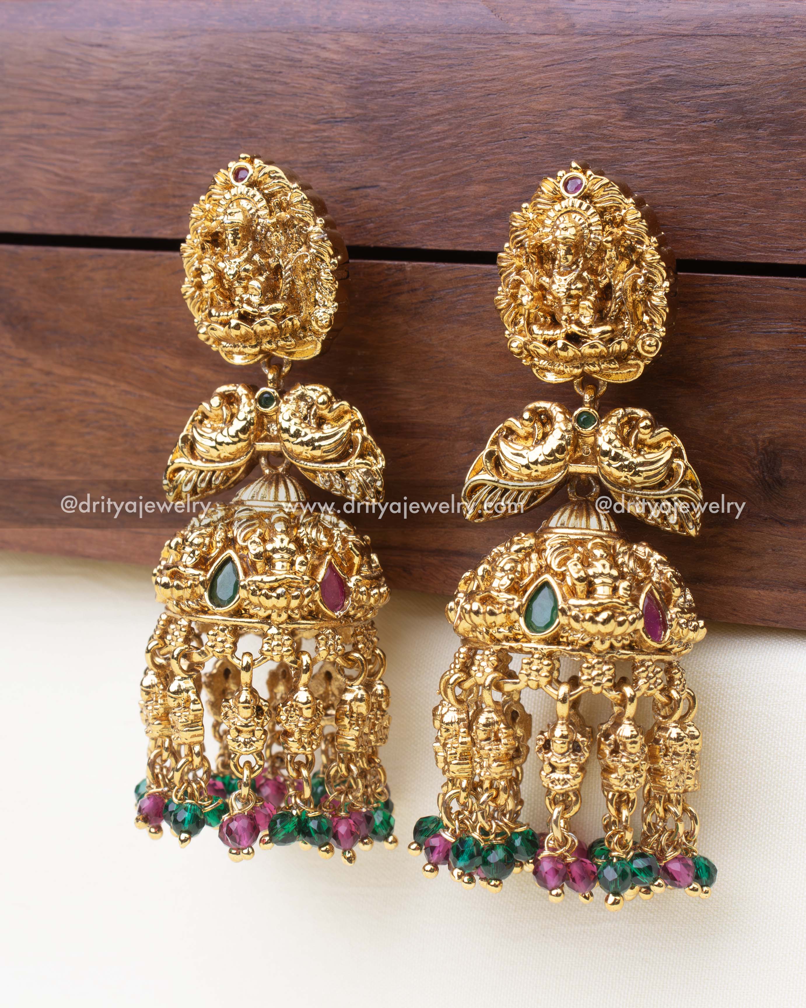 Gold-toned Nakshi jhumka earrings featuring Lakshmi Devi motif and colorful bead danglers.