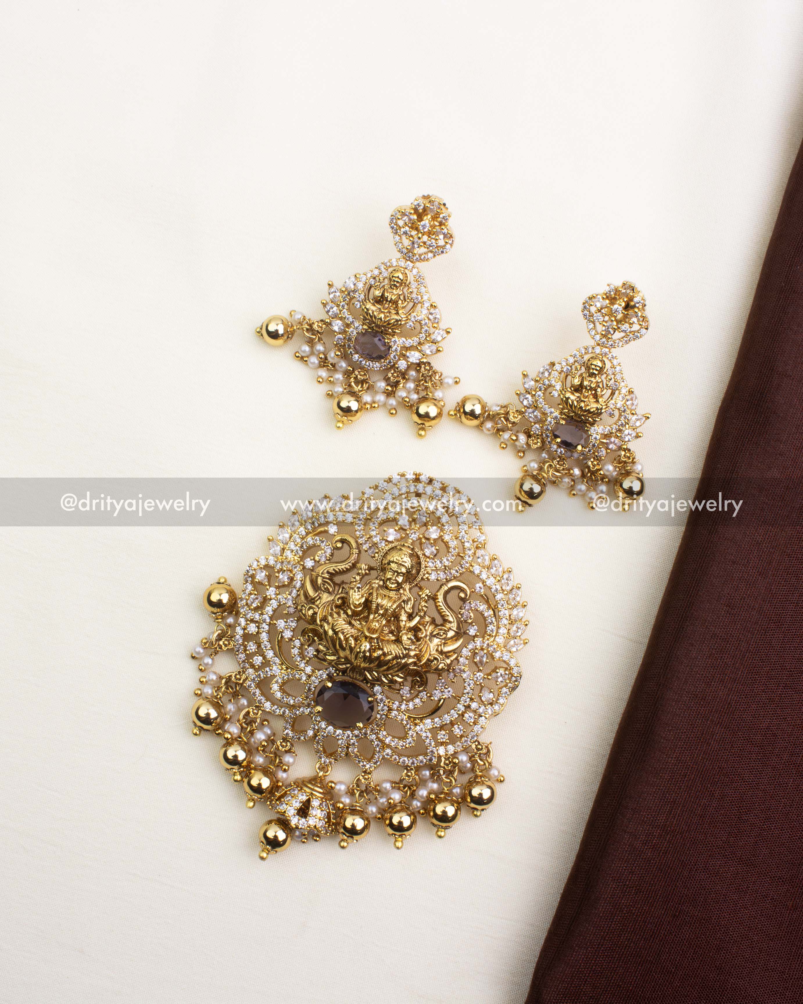 Temple pendant set featuring Lakshmi motif with CZ stones, pearls, and matching earrings.