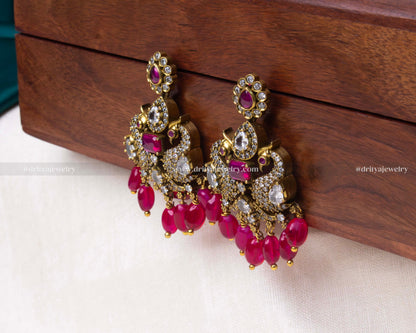 Elegant Victorian-style peacock motif earrings with pink bead hangings and faux gemstone embellishments, perfect for formal attire.