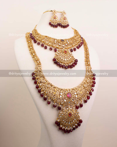 Complete bridal jewelry set with red kundan stones, maroon beads, and matching earrings.