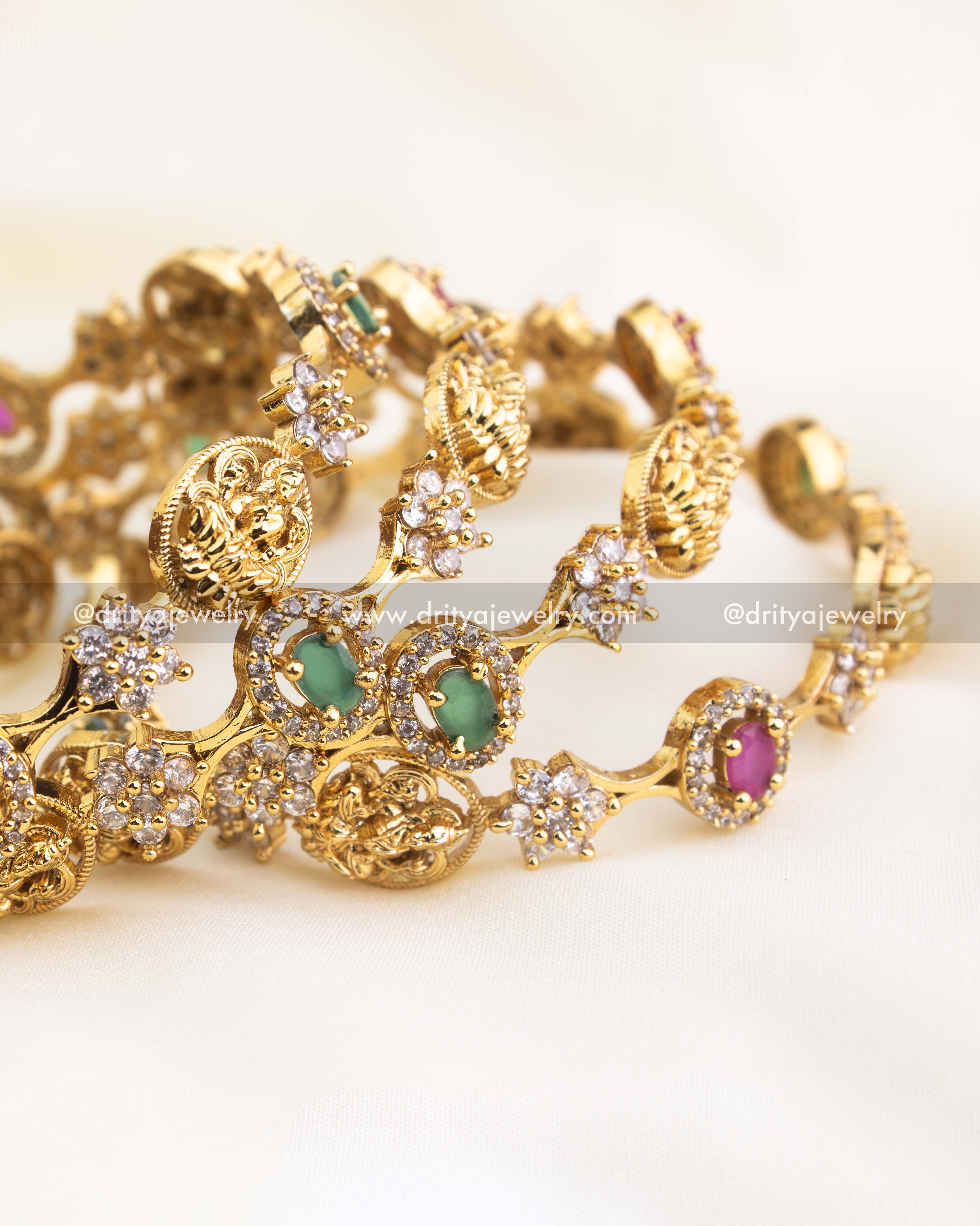 Antique gold-finished temple bangle set featuring alternating ruby and emerald stones with detailed Lakshmi motifs by Dritya Jewelry.