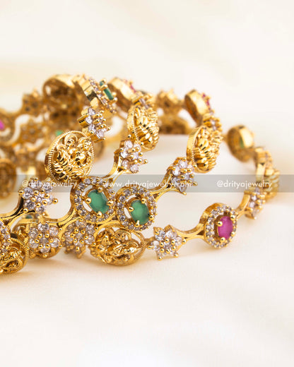 Antique gold-finished temple bangle set featuring alternating ruby and emerald stones with detailed Lakshmi motifs by Dritya Jewelry.