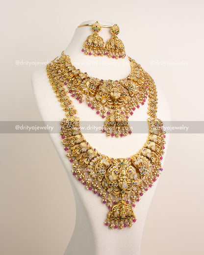 Antique gold temple bridal jewelry set featuring Lakshmi motifs, CZ stone accents, and ruby pink bead drops.