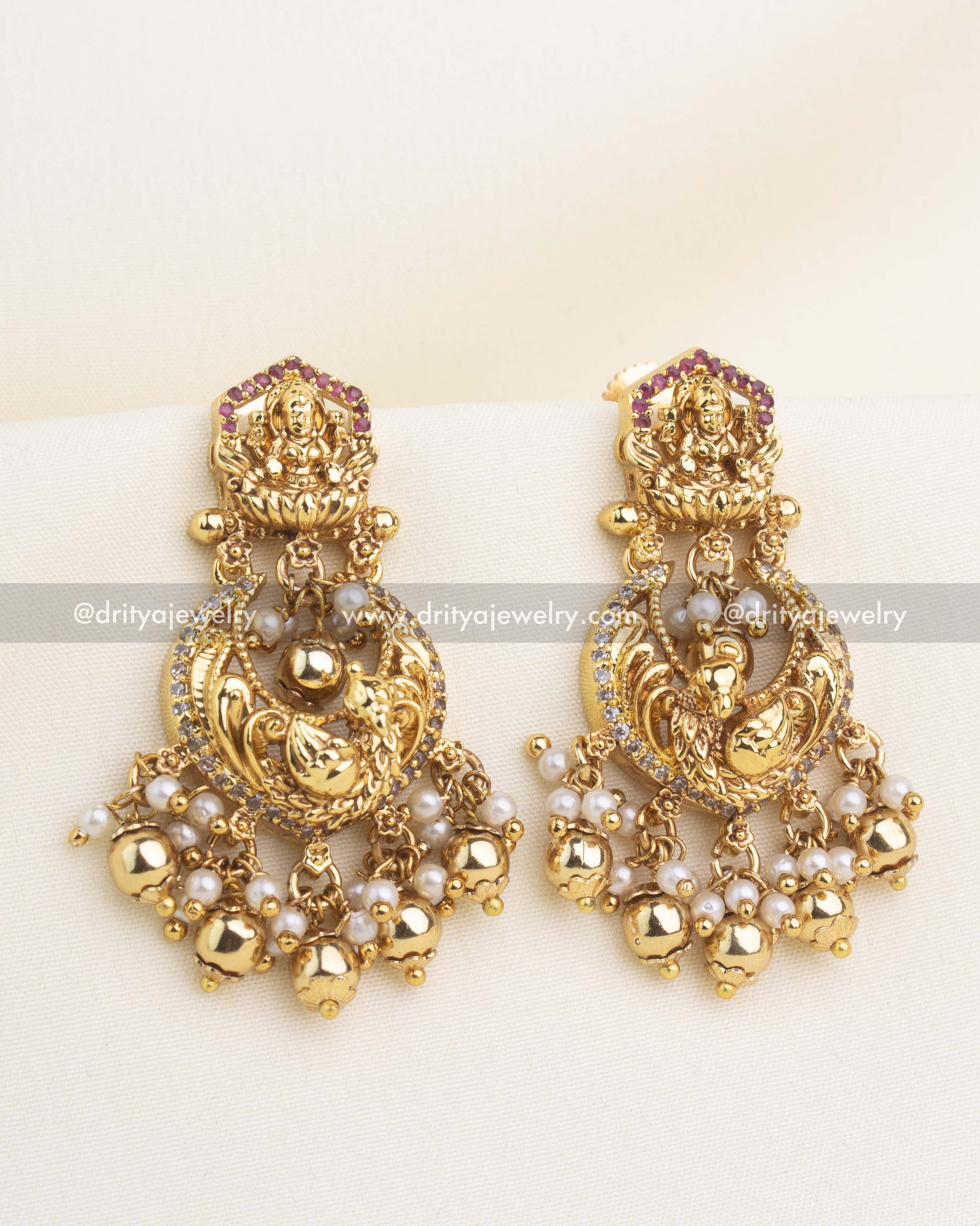 Gold temple chandbali earrings with Lakshmi motif, CZ stones, and pearl cluster hangings.