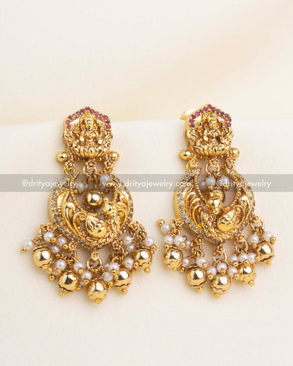 Gold temple chandbali earrings with Lakshmi motif, CZ stones, and pearl cluster hangings.