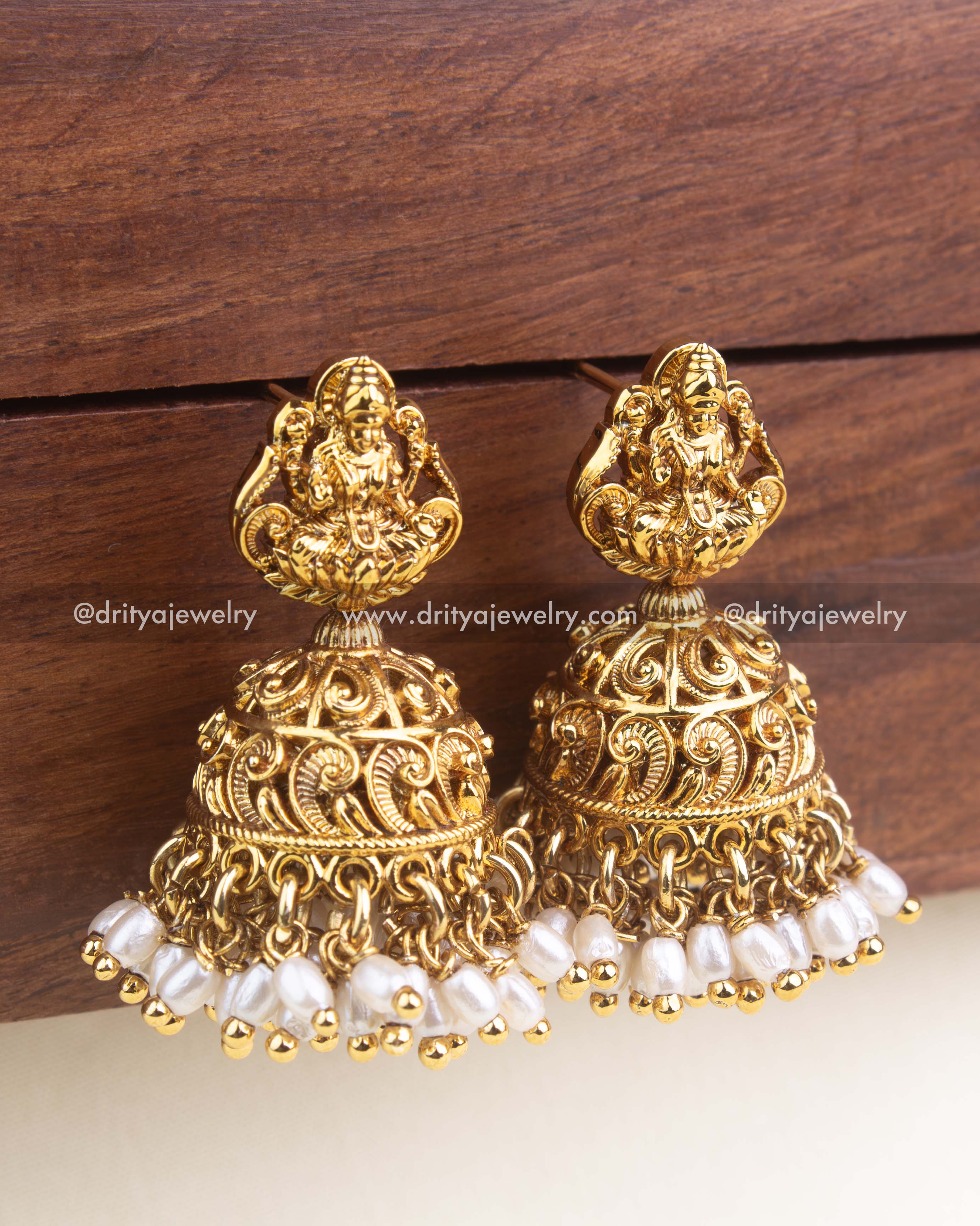 Close-up of nakshi temple jhumka showing intricate dome carving and rice bead pearl fringe.
