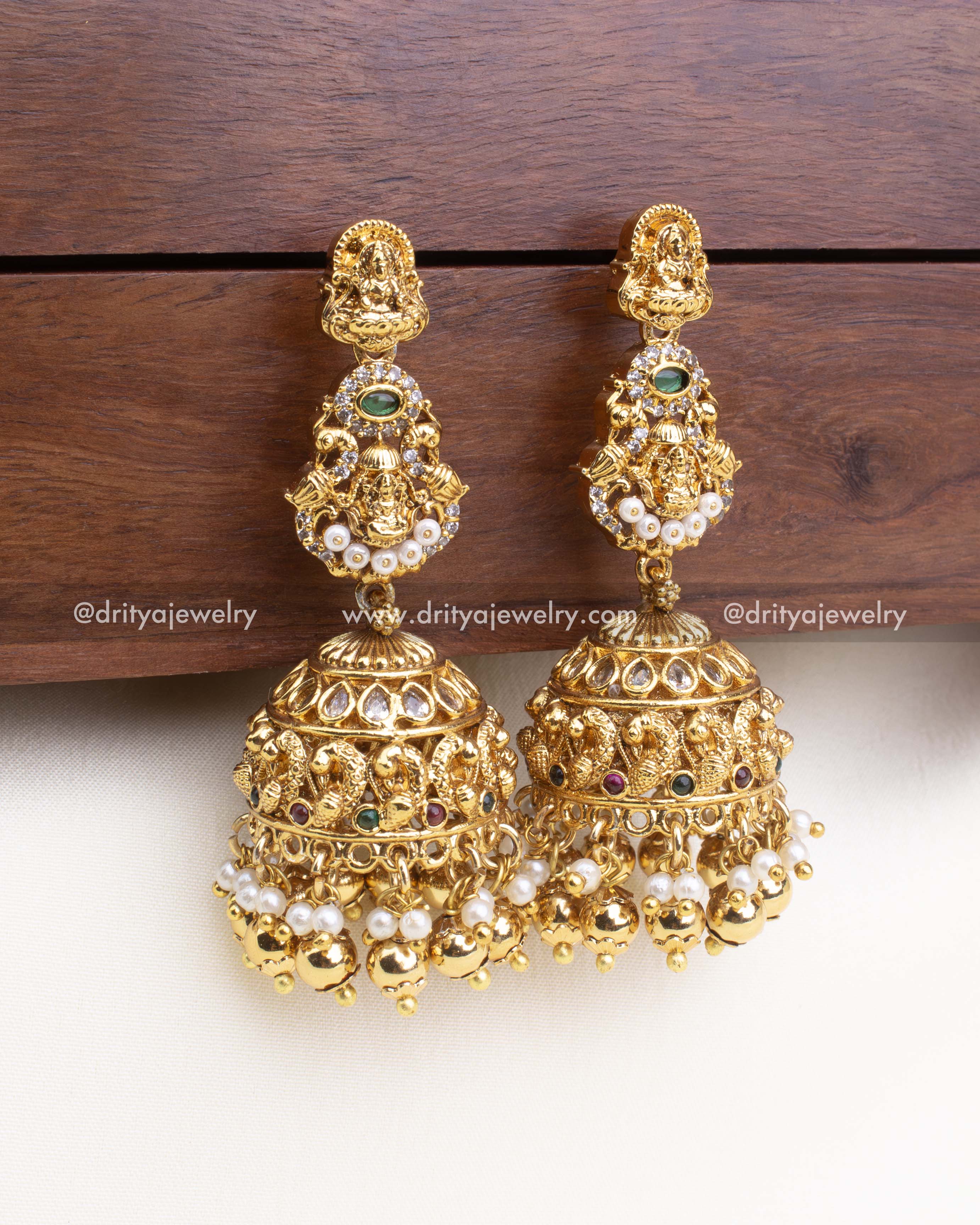 Detailed temple-style jhumka with deity carvings, multicolor stones, and dome hangings.