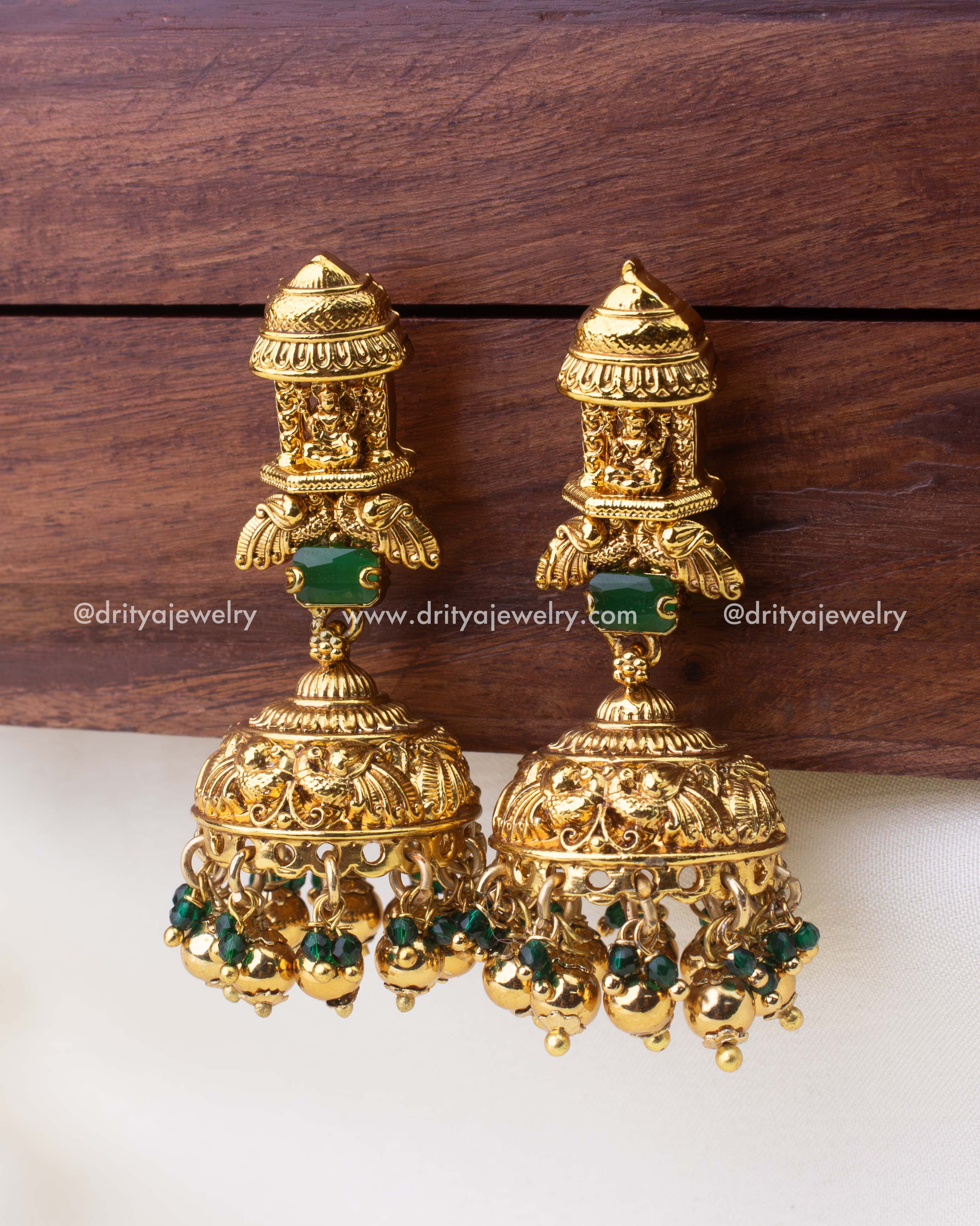 Ornate dome-shaped temple jhumkas with nakshi detailing and green bead hangings.