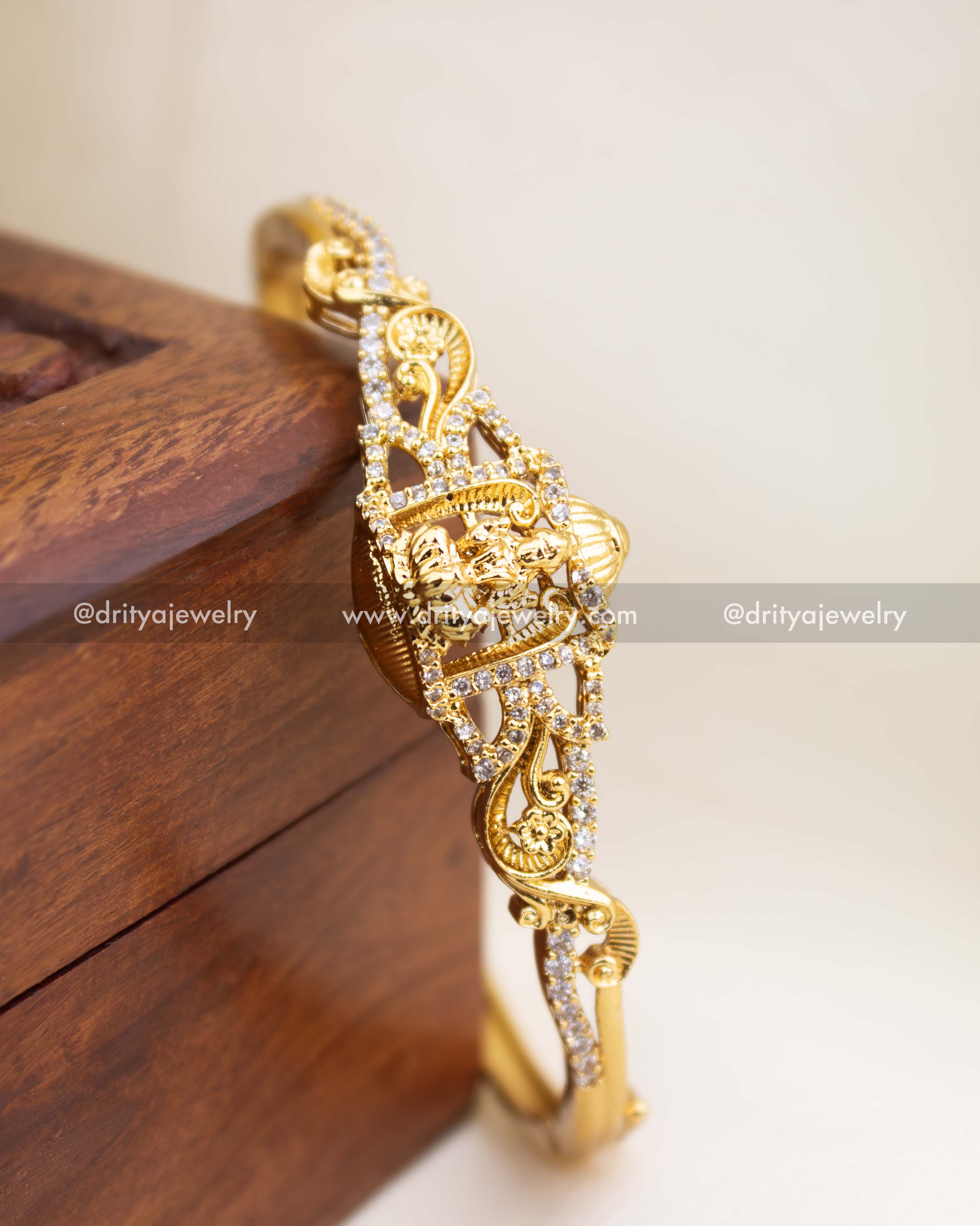 Openable temple kada with Lakshmi motif, gold polish, and CZ stone detailing.