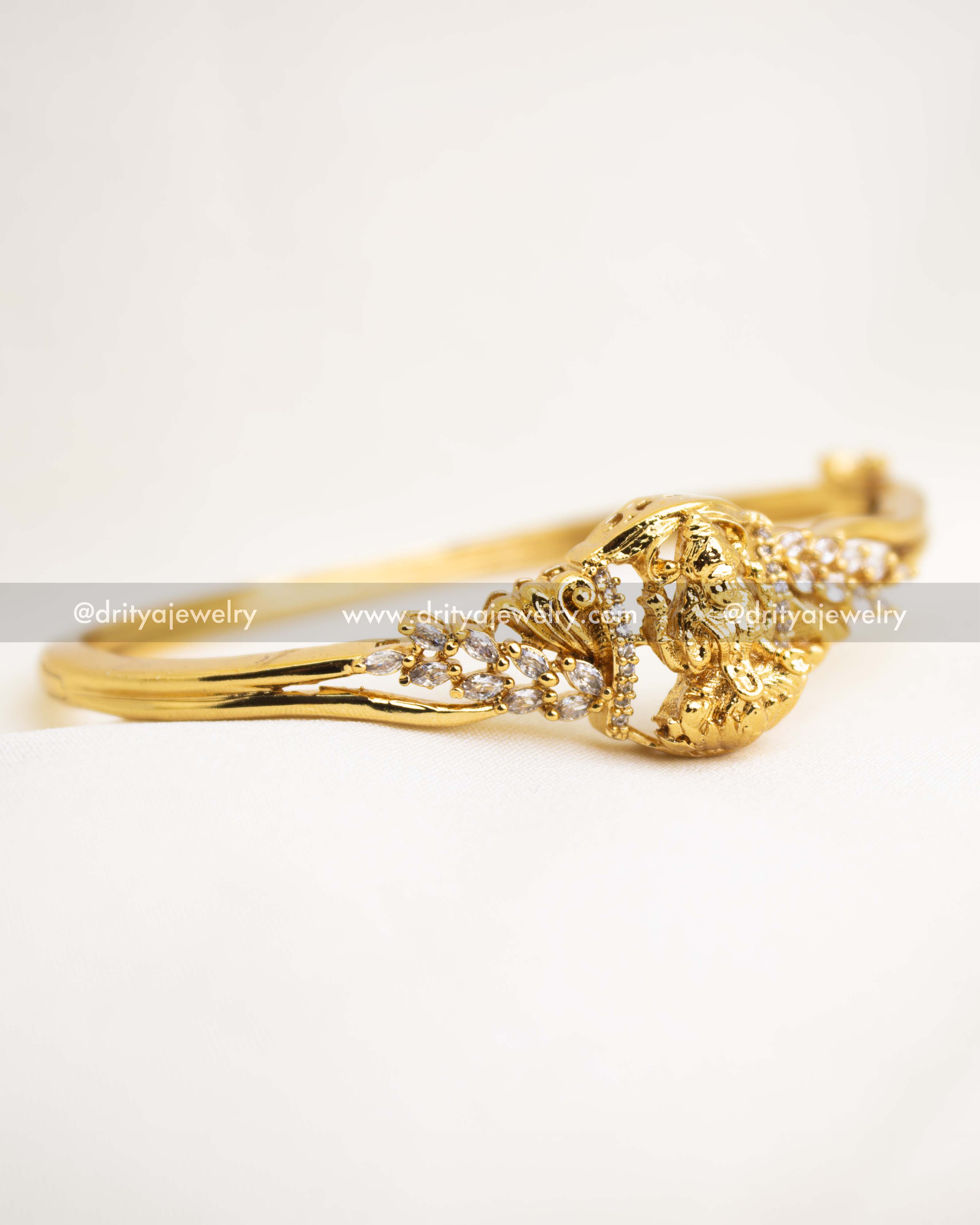 Openable temple kada featuring Lakshmi motif and CZ stone embellishments in antique gold finish.