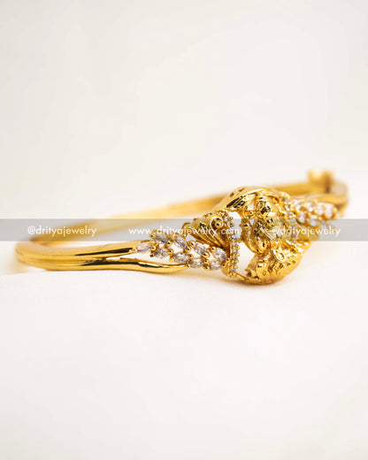 Openable temple kada featuring Lakshmi motif and CZ stone embellishments in antique gold finish.