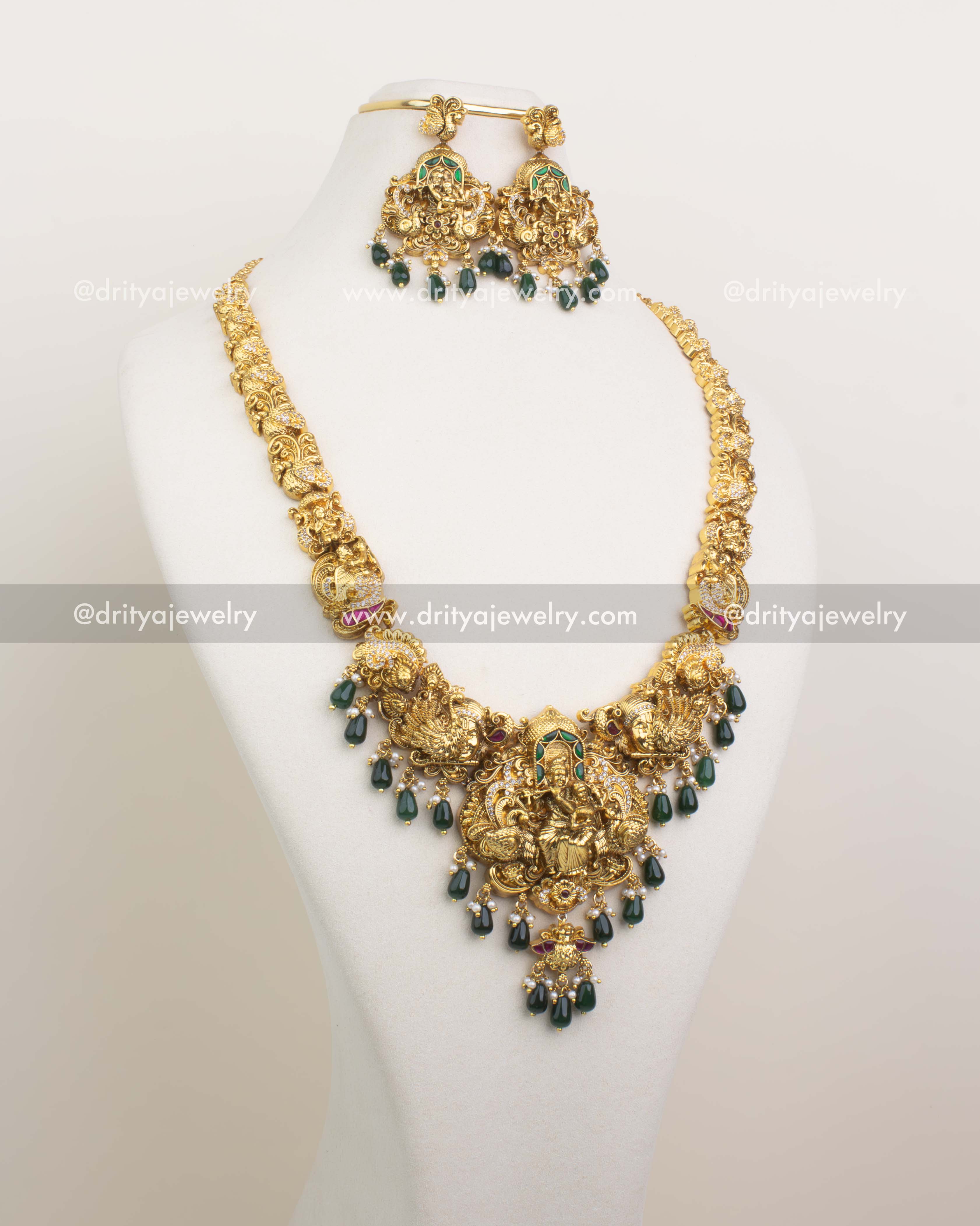 Long antique gold haram featuring Krishna-Parvati pendant and emerald green bead drops.
