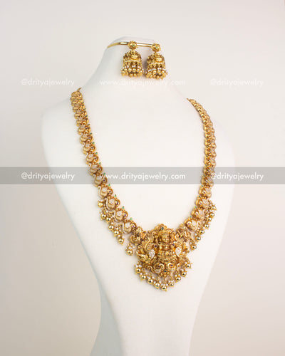 Gold-plated temple jewelry long necklace with Lakshmi pendant, pearl drops, and peacock motifs.